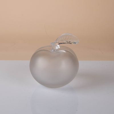 a glass apple with a leaf on it sitting on a table