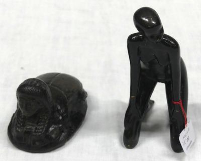 figurine of a man with a hat next to a black object on a white surface