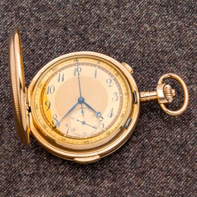 une montre de poche en or posée sur une surface grise