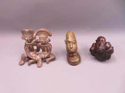 three figurines of different shapes and sizes on a white surface