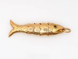 a gold fish pendant on a white surface