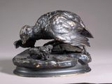 a bronze statue of a bird on a rock