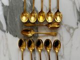 a lot of gold spoons and spoon spoons on a marble table