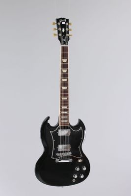 une guitare électrique noire accrochée à un mur blanc