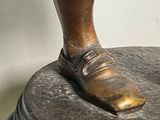 a bronze statue of a boy standing on top of a pedestal