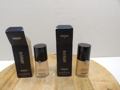 three bottles of makeup sitting on top of a wooden table