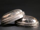 pair of silver plated objects on a black surface with a black background
