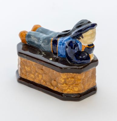 une figurine représentant un homme allongé sur une caisse