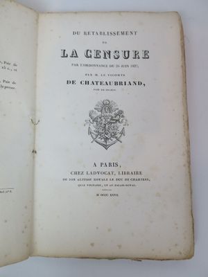 un livre ouvert posé sur une table, sur laquelle figure une image représentant des armoiries
