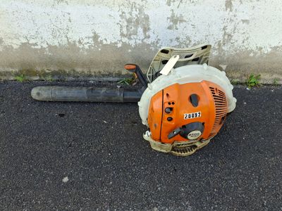 a chainsaw sitting on the ground next to a concrete wall