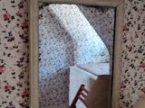 un miroir dans un coin d'une pièce où se trouvent une chaise et une lampe