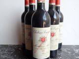 four bottles of red wine are lined up on a table