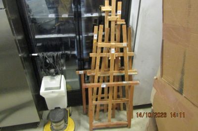 une pile de chaises en bois à côté d'un réfrigérateur dans une pièce