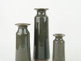 three green vases sitting next to each other on a white surface