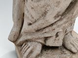 statue of a woman sitting on a stone block with her hands on her knees