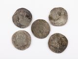 five silver coins are arranged in a row on a white surface