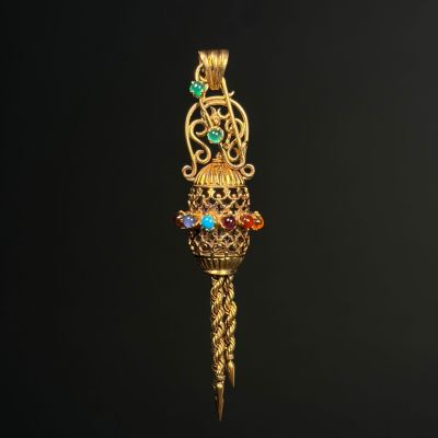 a close up of a gold pendant with colorful stones on it