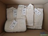 trois sacs de pulls dans une boîte, avec leurs étiquettes de prix