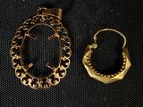 deux bijoux en or posés sur un tissu noir