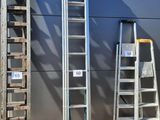 several ladders are lined up against a wall in front of a building
