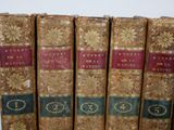 several old books are lined up in a row on a shelf
