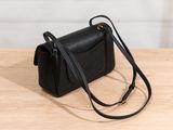 the small black bag is sitting on a wooden table