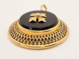 a black and gold pendant with a flower on it