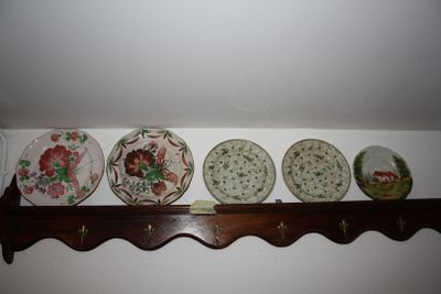 four plates on a shelf with hooks on the wall