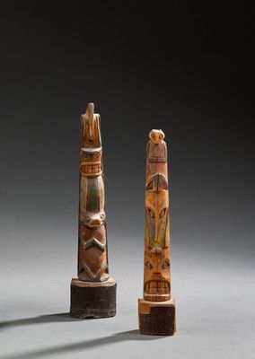 two carved wooden sculptures of a man and woman on a pedestal
