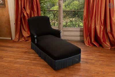 une chaise longue devant une fenêtre, dans une pièce