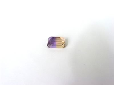 un gros plan d'une bague violette et dorée posée sur une surface blanche