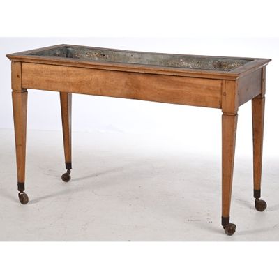une vieille table en bois avec un plateau en marbre, montée sur roulettes