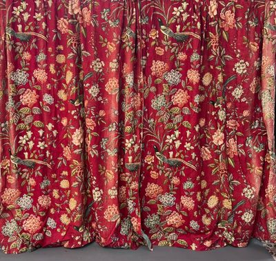red curtain with floral pattern hanging on a wall next to a window