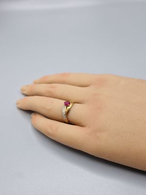 la main de quelqu'un, à laquelle est passée une bague en or sertie d'une pierre rouge