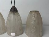 three glass bell shaped vases sitting on top of a white table