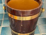 a wooden bucket filled with liquid sitting on a tiled floor