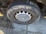 a close up of a tire on the side of a yellow bus