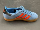 blue and orange adidas sneakers on a gray surface