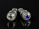 a pair of silver and blue glass stud earrings on a black surface
