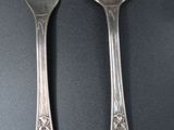 two silver spoons and a fork on a table