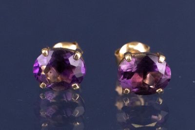 une paire de boucles d'oreilles en amethorate posées sur une surface noire