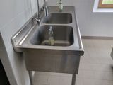 a stainless steel sink in the corner of a bathroom