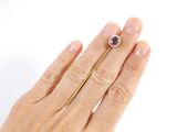 a woman ' s hand holding a ring with a purple stone