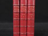 three red books sitting on top of each other on a black surface