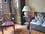 un salon avec un canapé, un fauteuil, une table, une lampe et un meuble