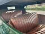 an old green car with leather seats and a baseball bat in the back seat