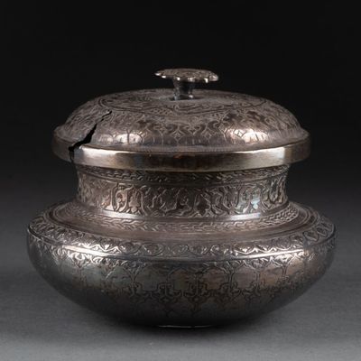 un vieux vase en argent muni d'un couvercle, sur fond noir