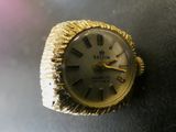 une bague en or sur laquelle est posée une montre, posée sur une table
