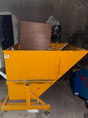 a yellow dumpster sitting in a garage next to a blue machine