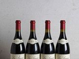 quatre bouteilles de vin sont alignées sur une table en bois